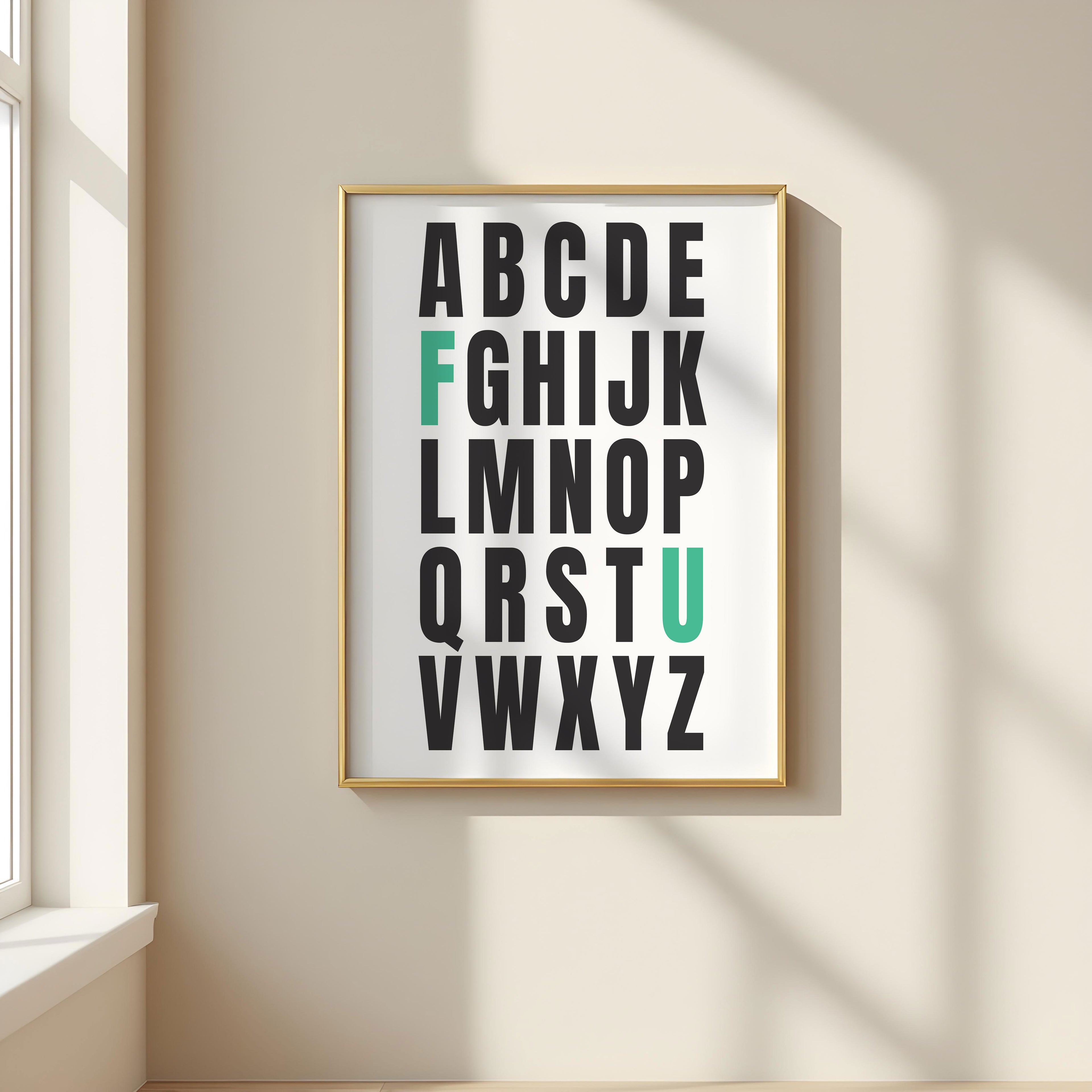 Framed alphabet poster with the letters F and U highlighted in teal on a wall with a window in the background.