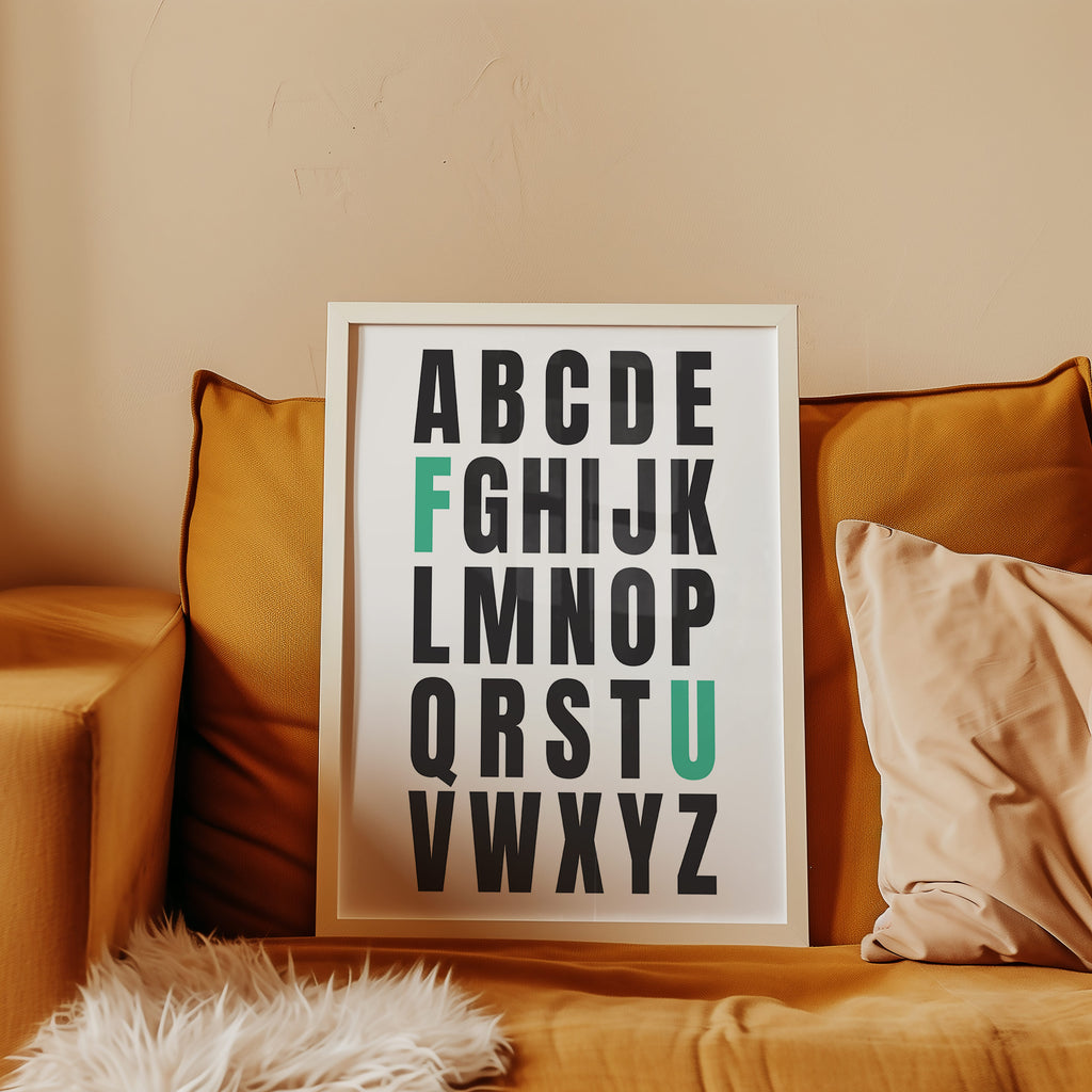 Framed alphabet poster with the letters F and U highlighted in teal on a couch with pillows.