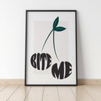 Framed artwork with a cherry design and 'BITE ME' text on a white wall.