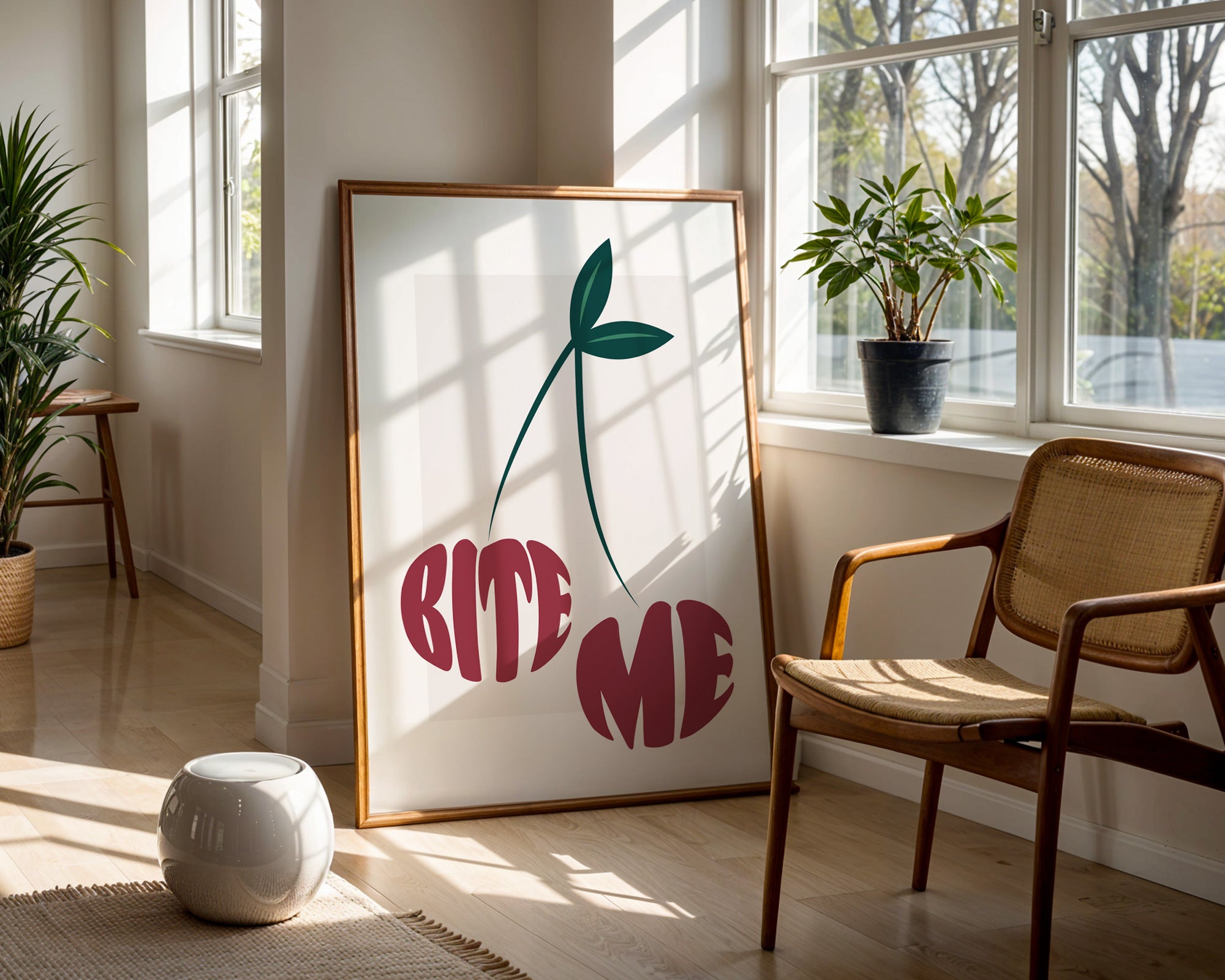 Room interior with a framed artwork of the words 'Bite Me' in the shape of two cherries in a sunlit room.