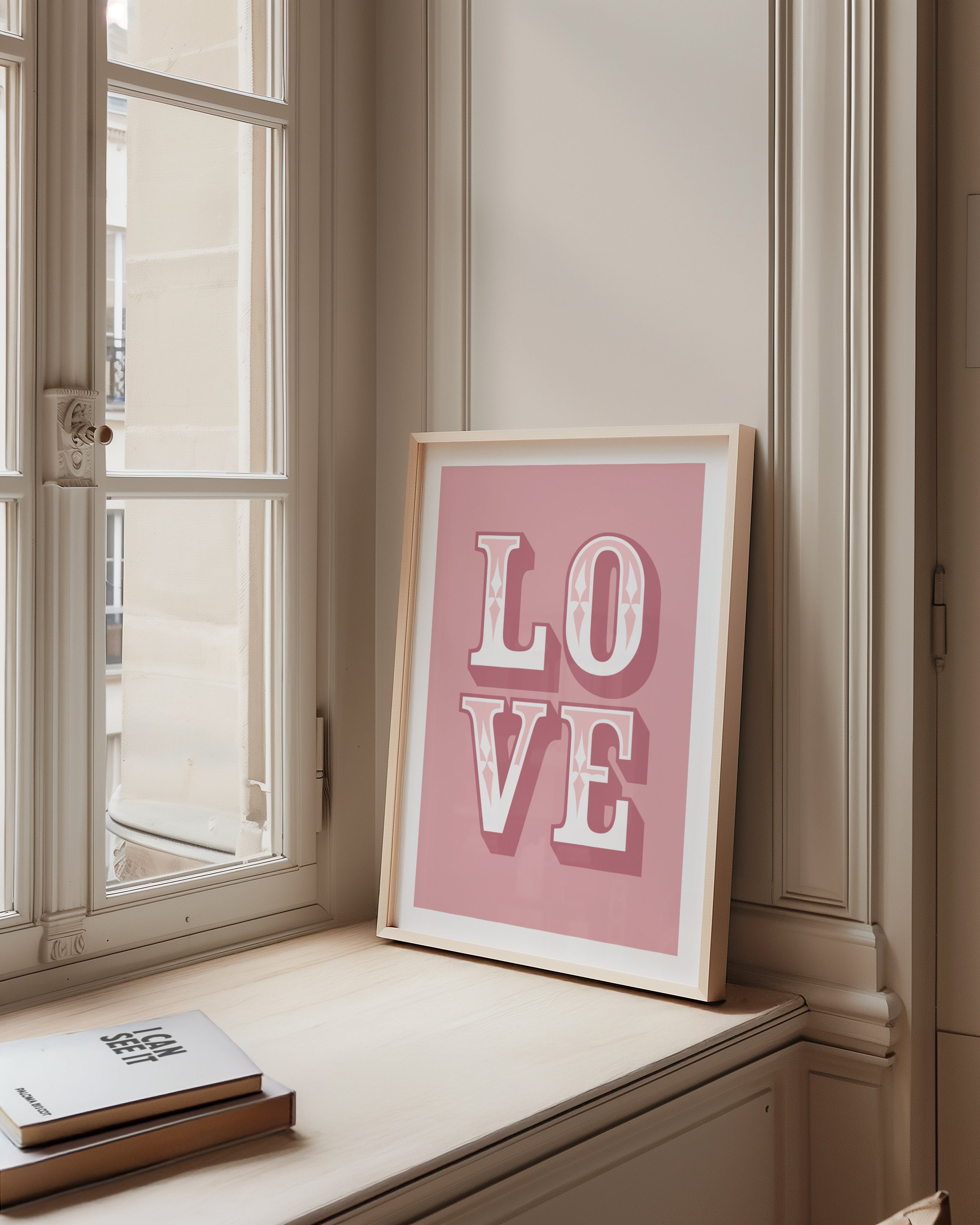 Framed 'LOVE' poster on a windowsill with books below