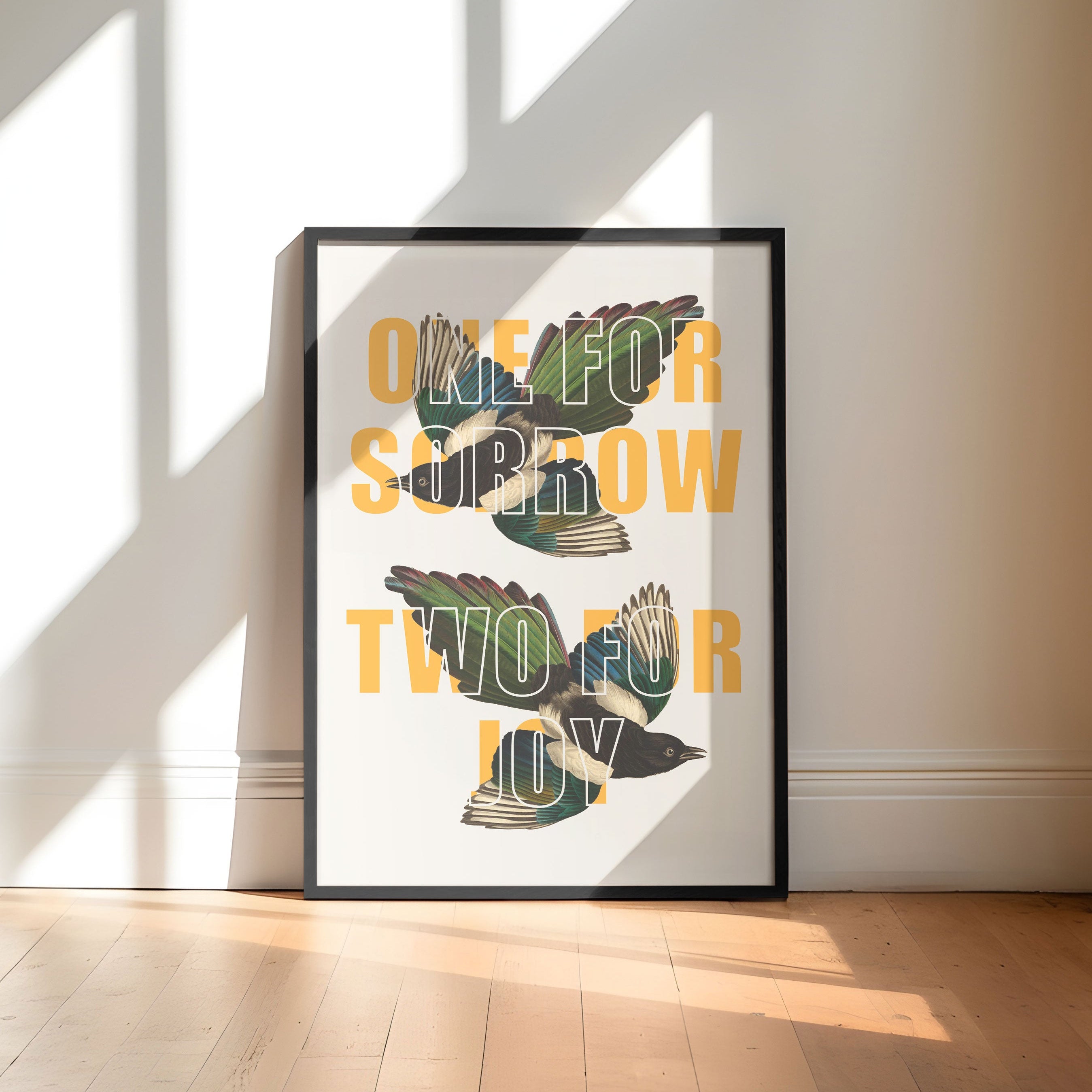 Framed artwork with text and magpie design on a wall in a bright room with sunlight streaming in.