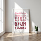 Framed poster with text saying 'Bad Mannered, Bad Tempered, Outrageous Female' in a minimalistic room with a plant.