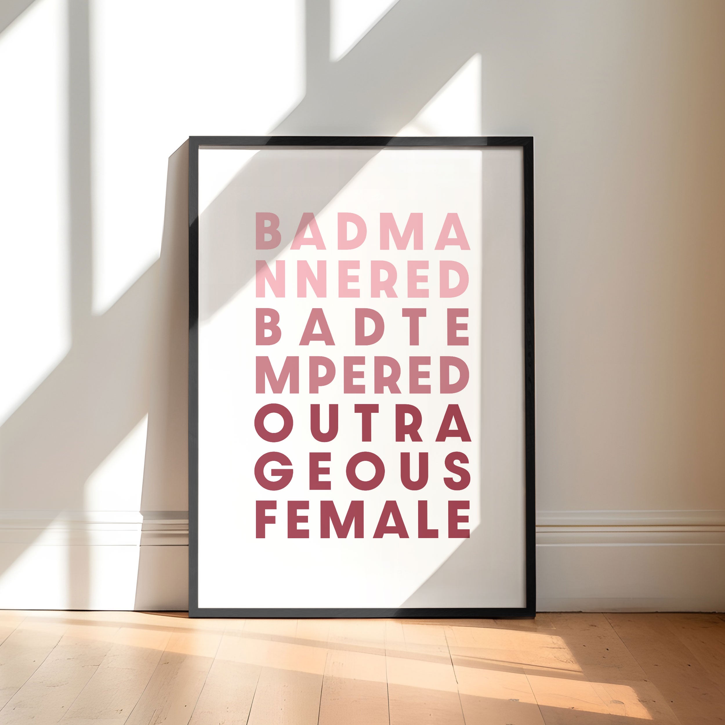 Framed poster with text saying 'Bad Mannered, Bad Tempered, Outrageous Female' on a white background.
