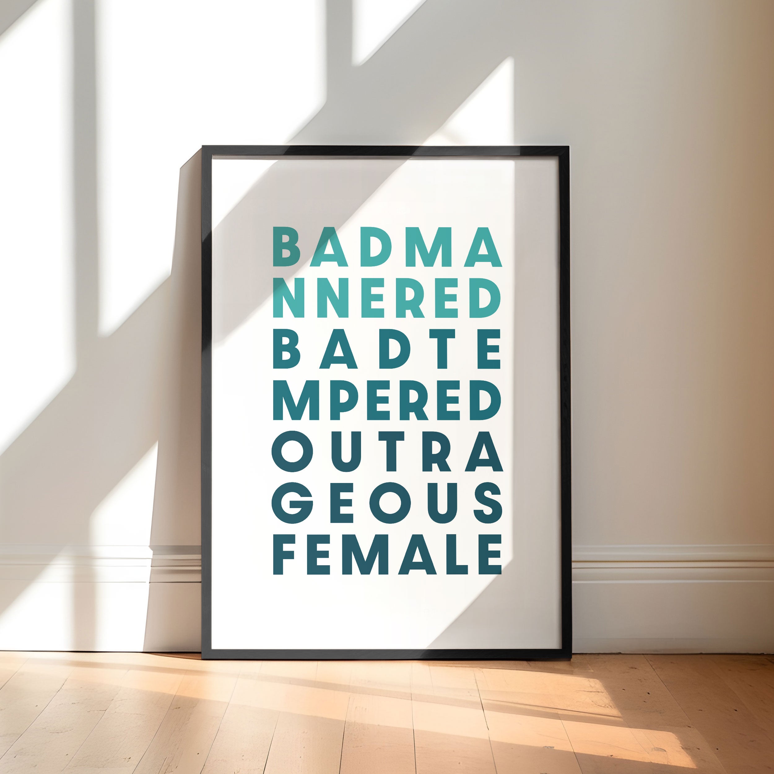 Framed poster with text saying 'Bad Mannered, Bad Tempered, Outrageous Female' on a white background.