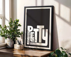 Framed artwork with the word 'PETTY' on a wooden shelf with plants