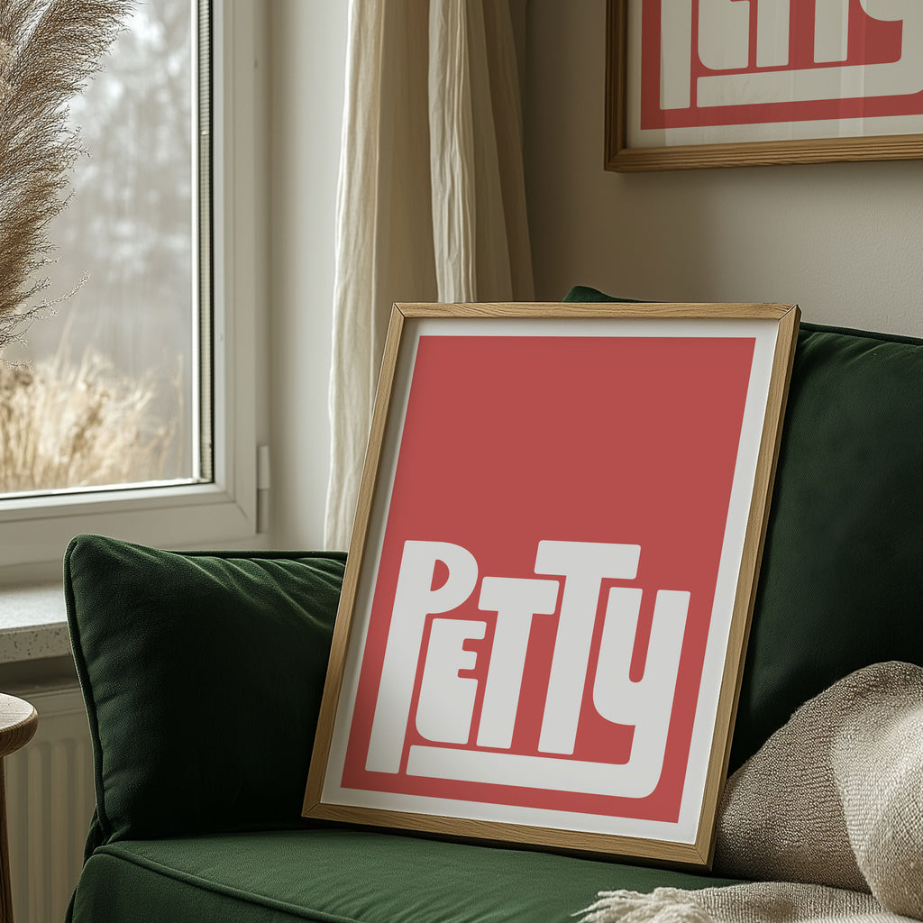 Framed artwork with the word 'PETTY' on a green couch next to a window.