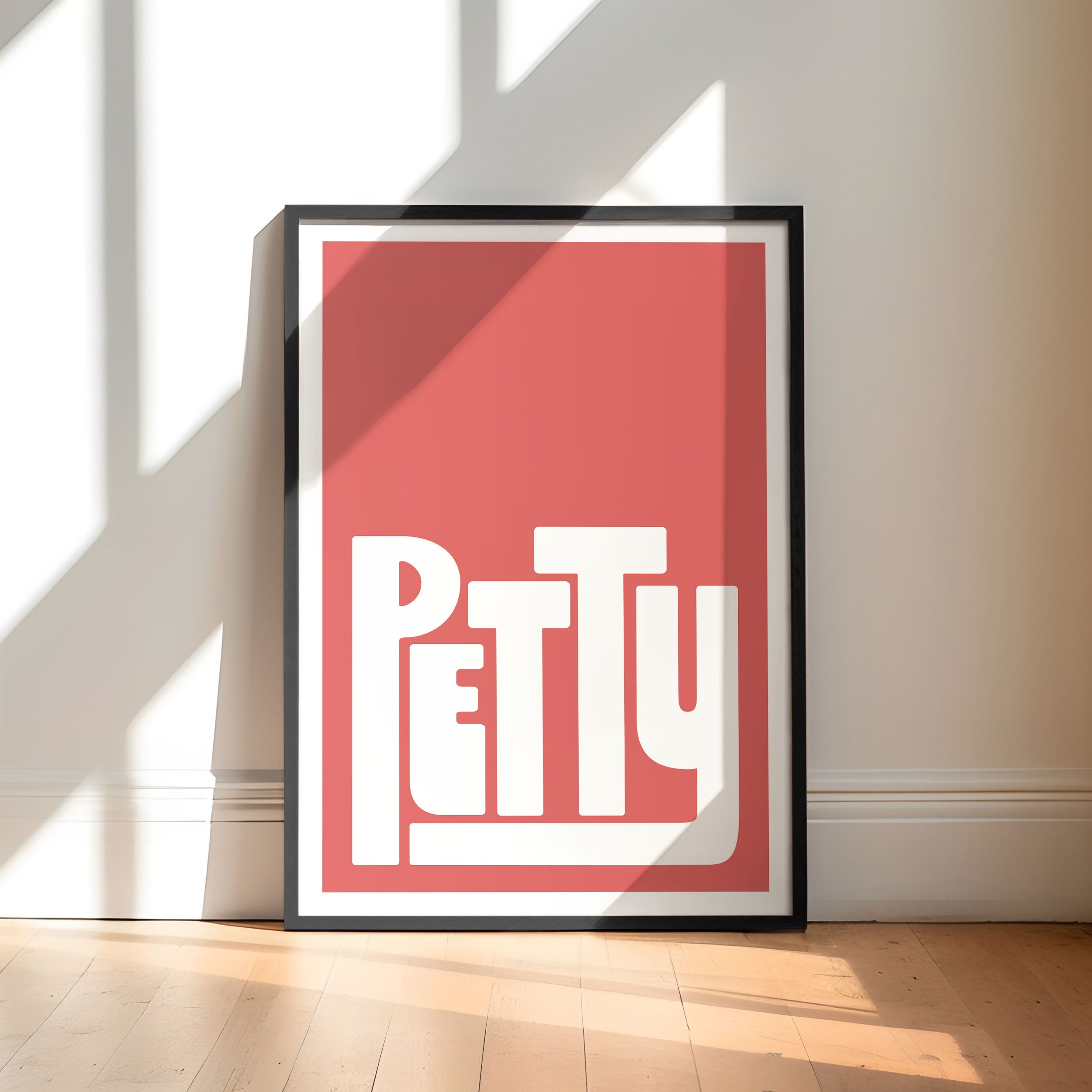 Framed poster with 'PETTY' design on a red background in a minimalistic room.