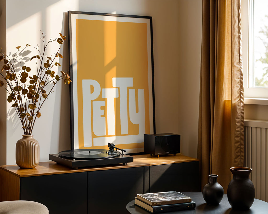 Record player with 'PETTY' poster on a wooden cabinet in a room with natural light.