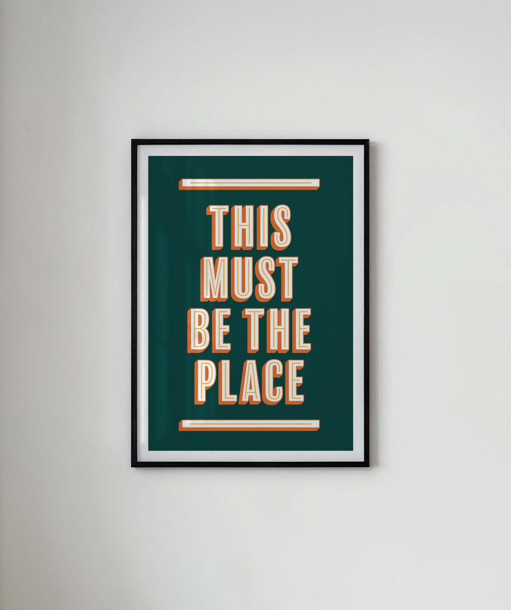 Framed poster with 'This Must Be the Place' text on a white wall.
