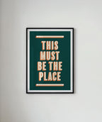 Framed poster with 'This Must Be the Place' text on a white wall.