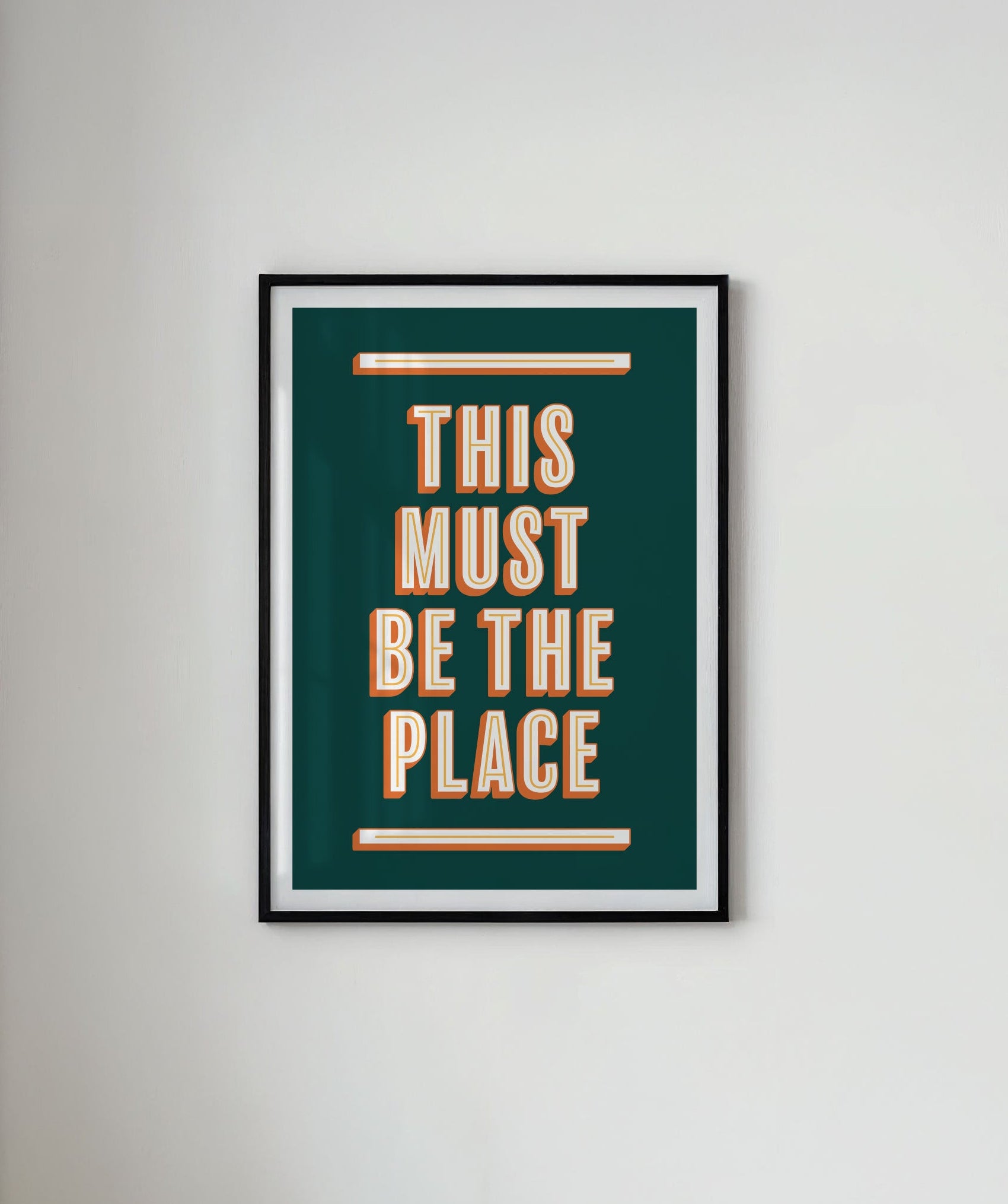 Framed poster with 'This Must Be the Place' text on a white wall.