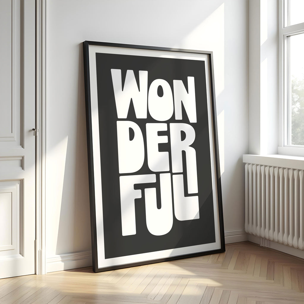Framed artwork with 'WONDERFUL' text on a black background in a room with a window and radiator.