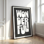 Framed artwork with 'WONDERFUL' text on a black background in a room with a window and radiator.