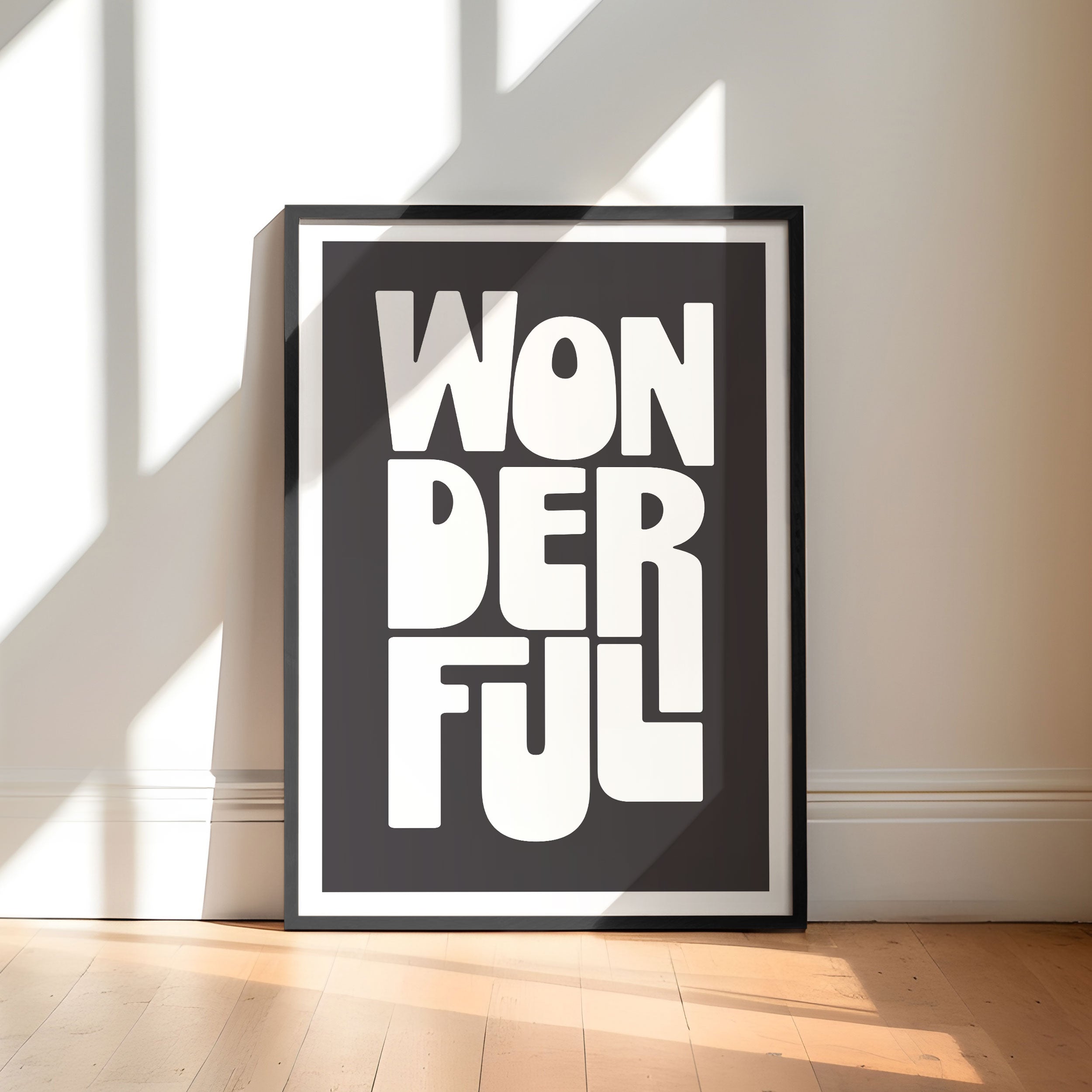 Framed poster with 'WONDERFUL' text on a wall with sunlight casting shadows.