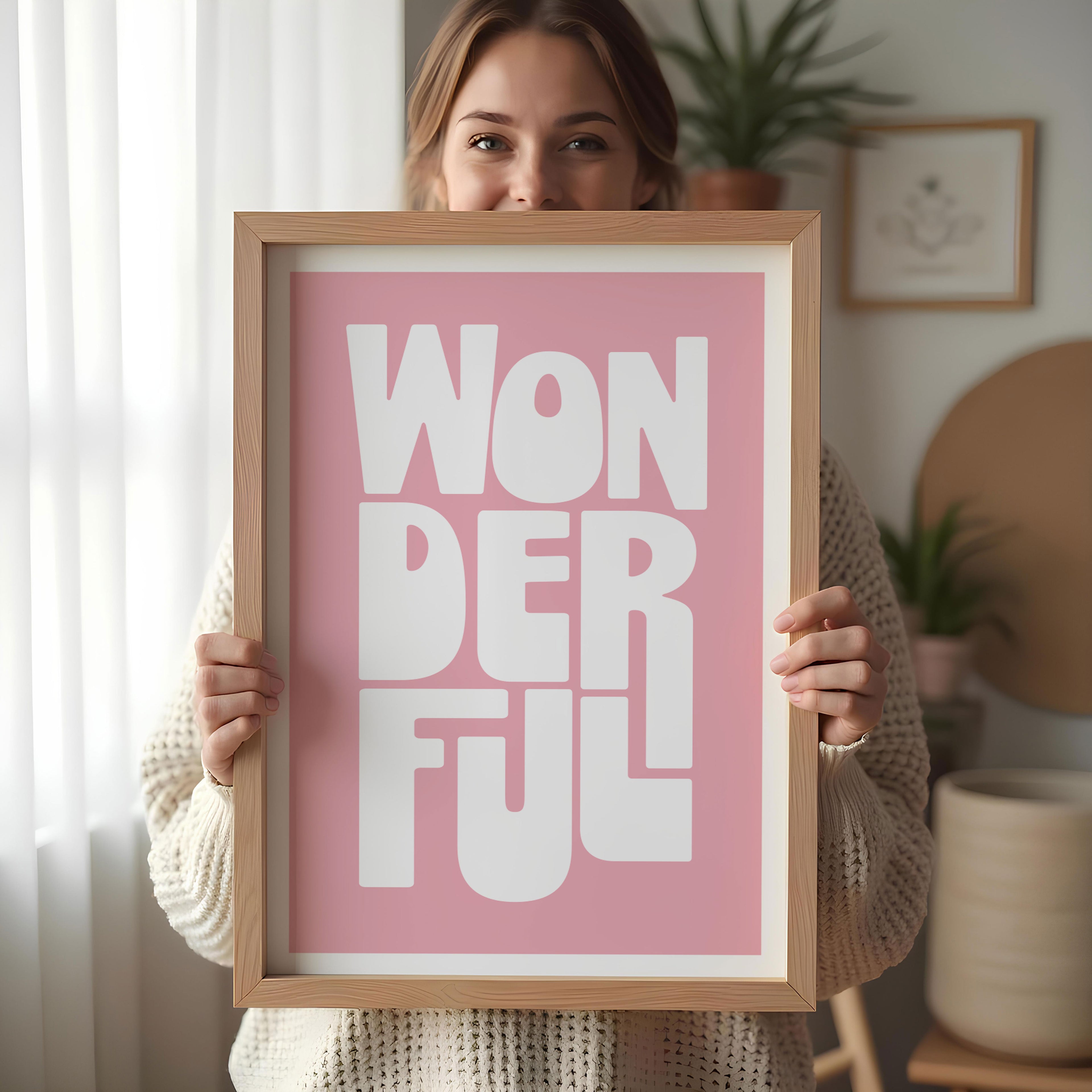 Person holding a framed poster with 'WONDERFUL' text on a pink background