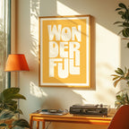 Framed artwork with 'WONDERFUL' text in a room with plants and a lamp.
