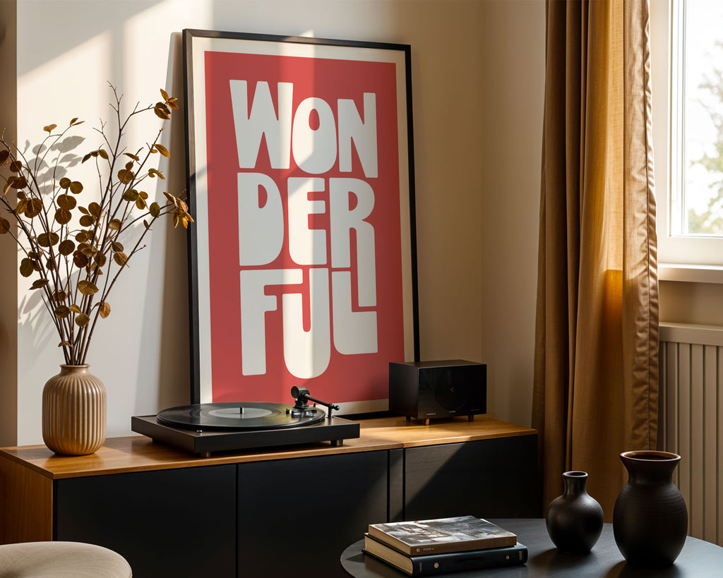 Turntable with a 'Wonderful' framed poster on a wooden cabinet in a room with a window.